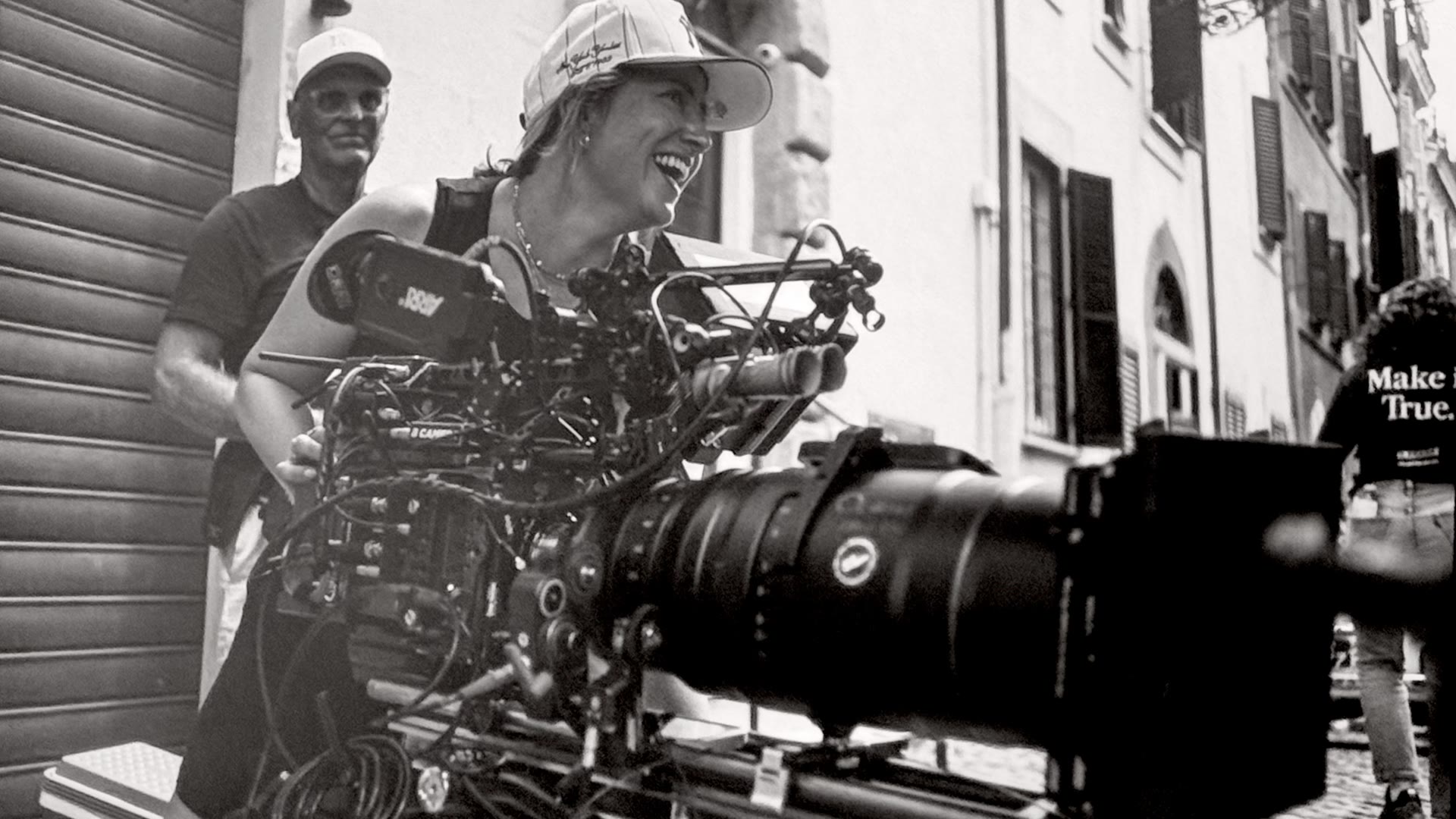 Angelia Hughes laughing while operating a camera rig on a narrow street.
